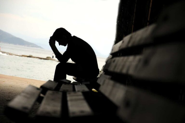 man seated on bench dealing with post traumatic stress disorder